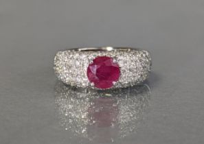 A ruby & diamond ring, the round mixed-cut ruby between broad pavé-set diamond shoulders, set to a