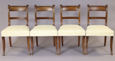 A set of four Georgian mahogany dining chairs with reeded bow-backs on scroll supports, padded seats