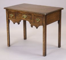 A Georgian oak lowboy fitted three frieze drawers above a shaped apron, on square chamfered legs,