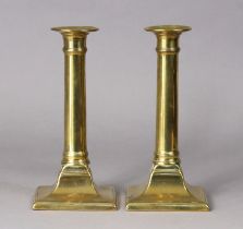A pair of late 18th century brass candlesticks, each with plain stem on flared square base, 20cm