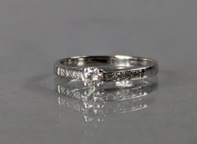 A diamond ring set brilliant-cut centre stone, rows of smaller stones to the shoulders, 18ct white