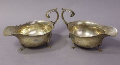 A pair of Edwardian silver oval sauce boats with cut-card rims, foliate C-scroll handles, each on