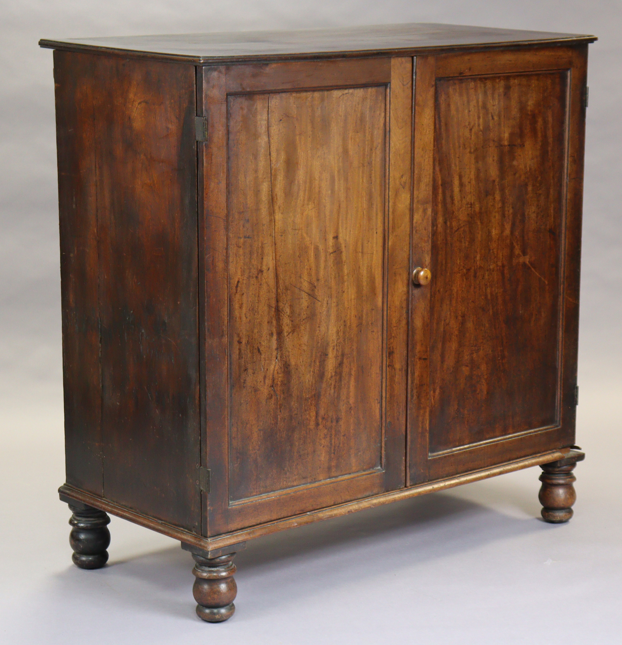 A Georgian mahogany hall cupboard, enclosed by a pair of fielded panel doors with turned handles,