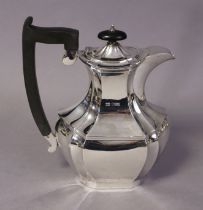 A George V silver coffee pot of oblong baluster shape, with short, curved spout, ebonised handle &