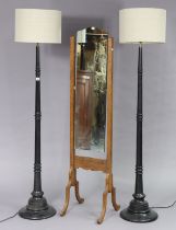 A pair of ebonised wooden standard lamps, each with a turned centre column, & on a stepped