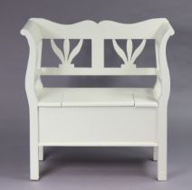 A white painted pine small box-seat settle with a pierced back, hinged seat, & on square supports,