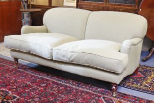 A Howard-style three-seater settee with a rounded back, scroll-arms, & with loose cushions to