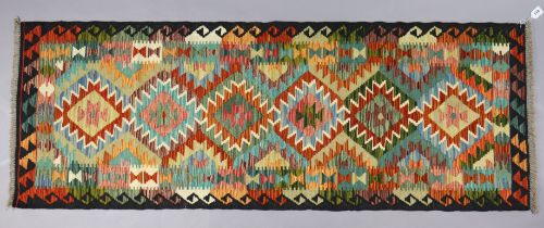 A Chobi Kilim runner with repeating multi-coloured geometric design to centre within a wide