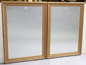 A pair of gilt frame rectangular wall mirrors each with a raised scroll border, & inset with a