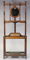 An Edwardian oak hallstand inset with a circular bevelled mirror to the top above a glove