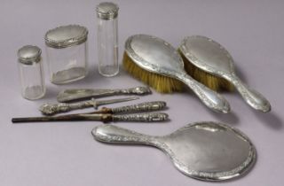 An Edwardian silver-backed three-piece part dressing table set each with an embossed scroll