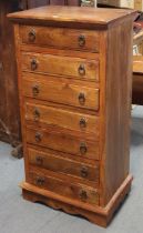 A teak small upright chest fitted seven long drawers with iron ring handles, & on a shaped plinth