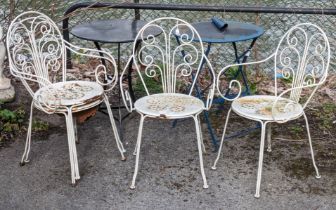 A set of four white finish wrought-metal patio chairs; & two patio tables.