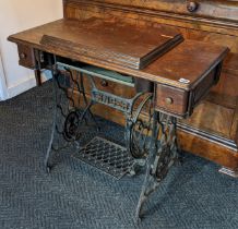 A Singer treadle sewing machine in an oak case; & on a black painted cast-iron base, 90.5cm wide x