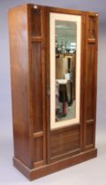 A late Victorian walnut wardrobe (lacking cornice) enclosed by a centre mirror door, & on a plinth