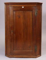 A 19th century oak hanging corner cupboard fitted three shaped shelves enclosed by a fielded panel