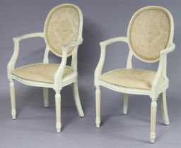 A pair of continental-style white painted wooden frame elbow chairs each with a padded seat &