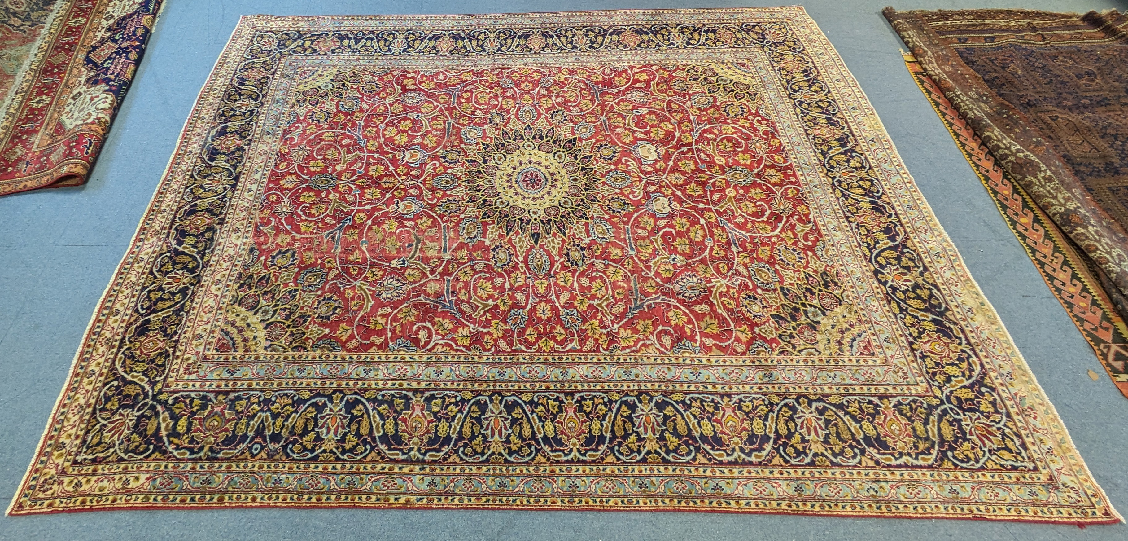 A Persian carpet of crimson ground featuring a central medallion, surrounded by floral motifs,