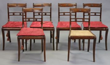 A set of six Regency mahogany dining chairs with carved foliate decoration to the bow-backs and cen