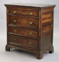 A late 17th century oak chest with panelled sides, fitted four long drawers with later brass swan-