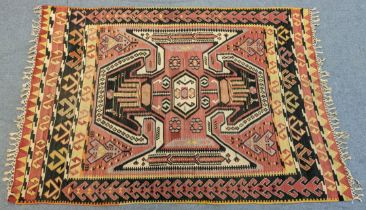 A Turkish Corum kelim rug, the pink ground centre with large stylized winged panel, within hooked