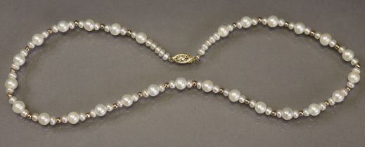 A single-row necklace of graduated cultured pearls with gold bands at intervals, the clasp marked “