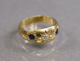 An 18ct. gold ring, gypsy-set with a diamond between two sapphires, Birmingham hallmarks for 1939;