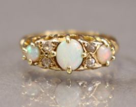 A yellow metal ring set three graduated oval opals with pairs of small diamonds in between, the