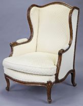 A Louis XV-style carved beech frame fauteuil with upholstered wing-back, arms and wide seat, on