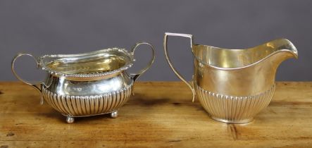 A Victorian silver oblong semi-fluted two handled sugar bowl with gadrooned rim, on four ball