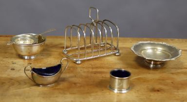 An Edwardian silver six-division toast rack with central square ring handle, on four bun feet,