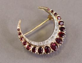 A 9ct gold crescent brooch set seventeen graduated oval-cut rubies & an inner border of small