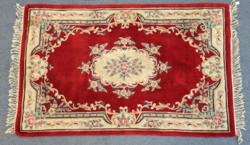A 20th century Chinese rug of crimson ground with central medallion within green and ivory floral