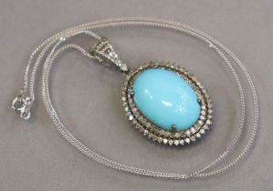 A large oval cabochon turquoise pendant set within a double border of small diamonds; the