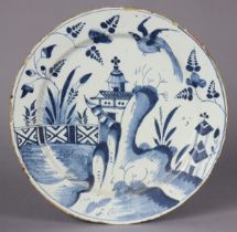 A mid-18th century English delft large dish, painted with a rim-to-rim chinoiserie landscape scene