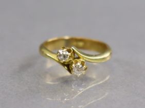 An 18ct. gold cross-over design ring set two small diamonds; size: I/J; 3.6gm.