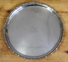 An Edwardian silver circular salver with raised beaded rim, engraved monogram to centre, & on