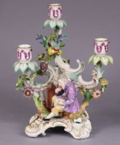 A 19th century Meissen porcelain candelabra figure of Paracelcius seated beside an oven, with three