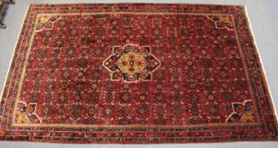 A Persian Malayer carpet of madder ground, with central medallion surrounded by repeating floral