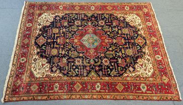 A Persian carpet of deep blue ground with central panel and scattered multi-coloured stylised