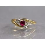 A gold cross-over design ring set round-cut ruby between two diamonds, hallmarks rubbed; size: F;