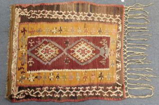 An antique Turkish tribal kelim rug of ochre ground featuring a pair of central medallions within