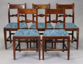 A set of five Georgian mahogany dining chairs with carved supports, padded seats, and square legs,