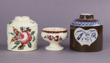 An 18th century English creamware cylindrical teapoy with boldly painted floral decoration in