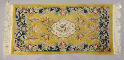 A 20th century small Chinese rug of yellow ground, featuring a central medallion surrounded by