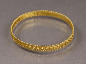 An Egyptian gold stiff bangle with continuous ‘nail-head’ design within coiled wire rims (20.5g).