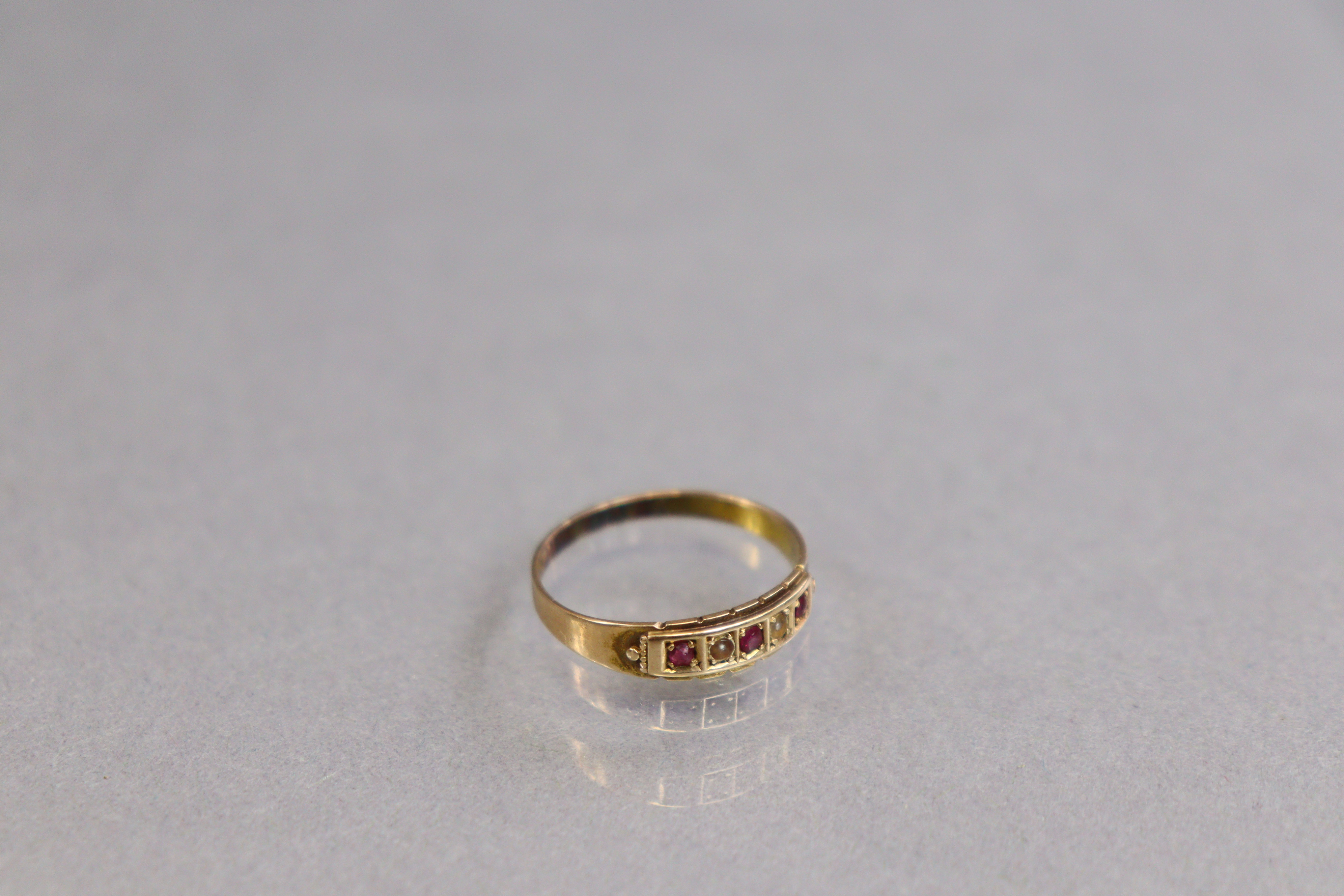 A 15ct. gold ring set row of three small rubies separated by two seed pearls; size: P; 1.7gm. - Image 2 of 3