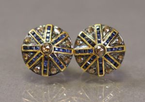 A pair of large circular wheel-design ear studs set numerous small diamonds & sapphires.