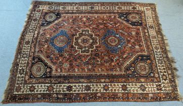 A Qashqai rug of rust-red ground, with row of three central panels and scattered multi-coloured