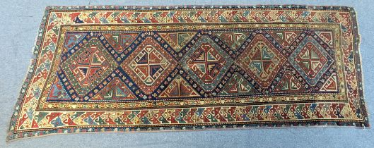 An antique Kazak runner with central row of five gul and all-over multi-coloured geometric